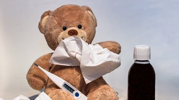 Kranker Teddy mit Taschentuch und Fieberthermometer